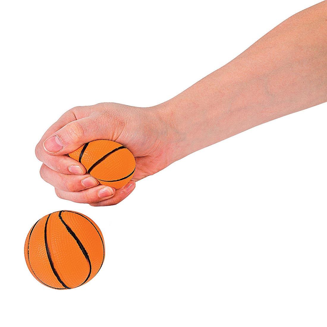 two Foam Realistic Basketball Stress Balls by Fun Express with a hand squeezing one of them