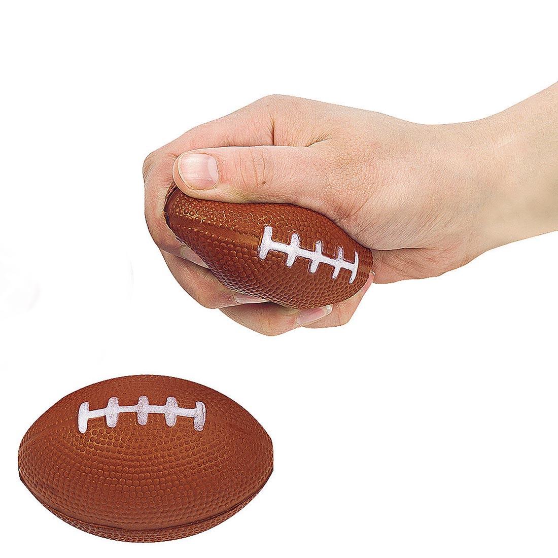 two Foam Realistic Football Stress Balls by Fun Express with a hand squeezing one of them