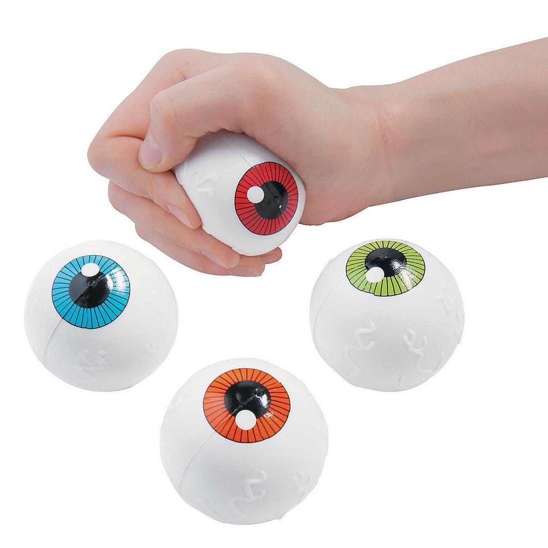 four Foam Eyeball Stress Balls by Fun Express with a hand squeezing one of them