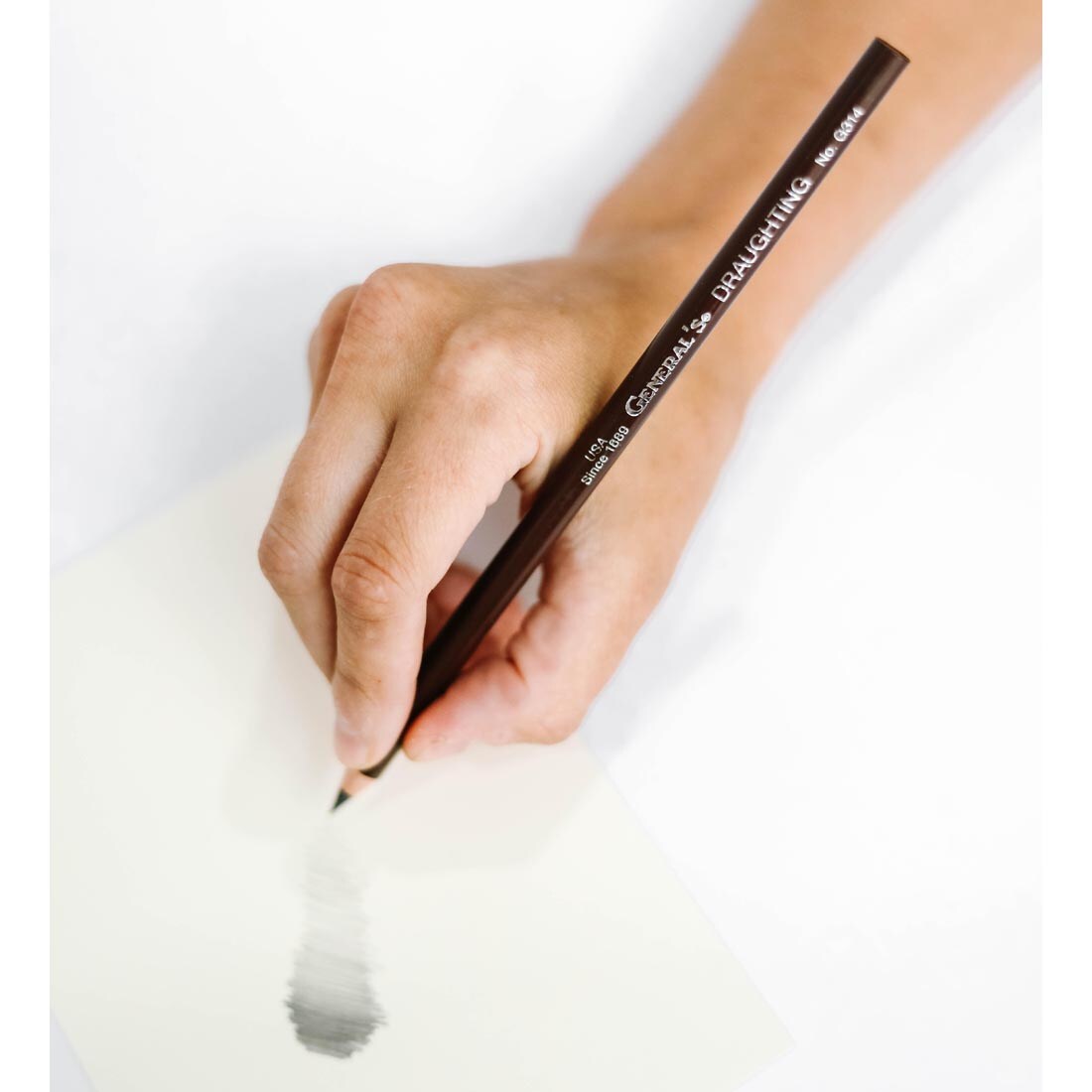 Hand holding General's Draughting Pencil with example of lead shading on paper