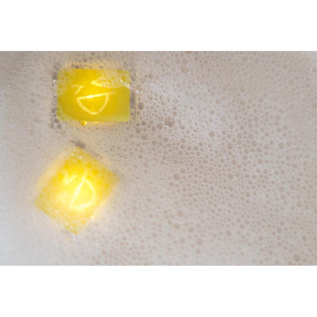 Alex Yellow Glo Pals Water-Activated Light Up Cubes floating in a bubble bath