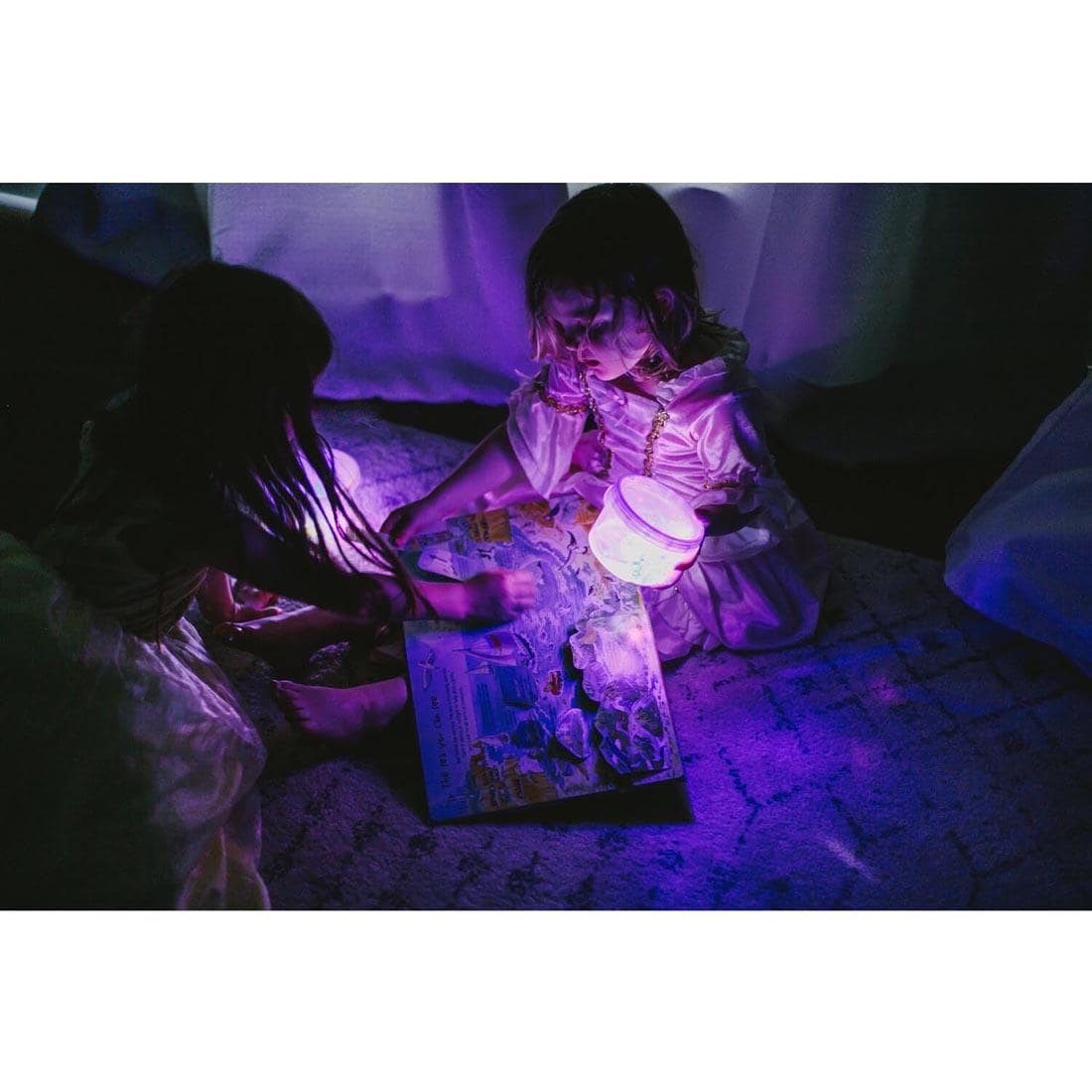 children on a bed looking at a book, holding a bowl of water containing Lumi Purple Glo Pals Water-Activated Light Up Cubes