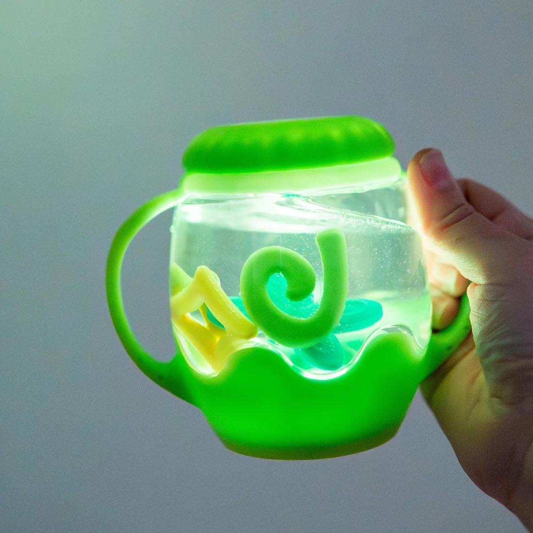 hand holding the Firefly Green Mini Sensory Play Jar By Glo Pals
