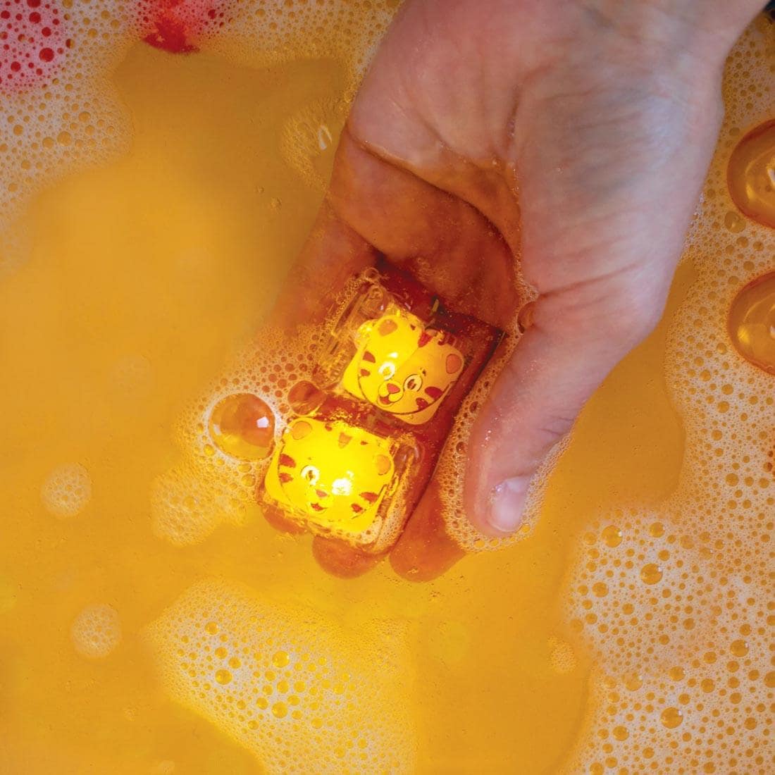 Hand holding Two Daniel Tiger Glo Pal Water-Activated Light-Up Cubes in water