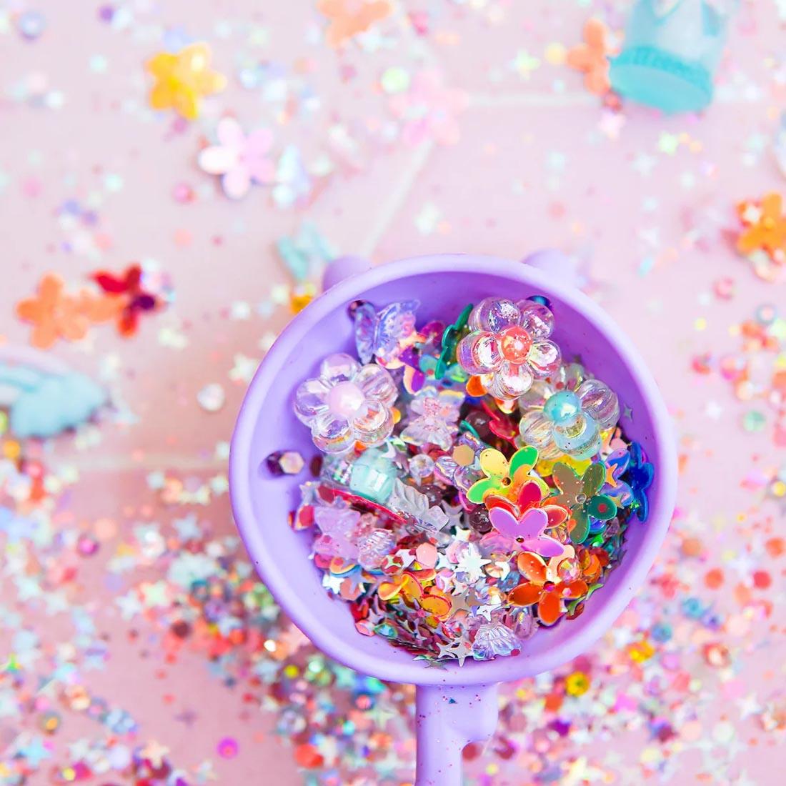 pieces from the Fantasy Fairy Sensory Play Fun Fillers By Glo Pals in and around a cup