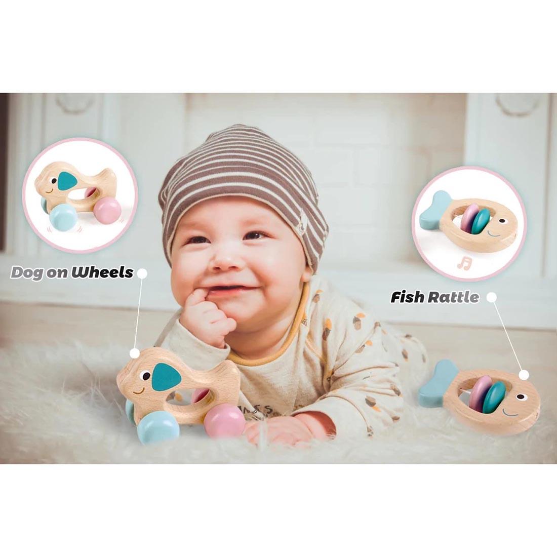 Baby next to pieces of the Wooden Multi-Stage Sensory Set with their labels Dog on Wheels and Fish Rattle