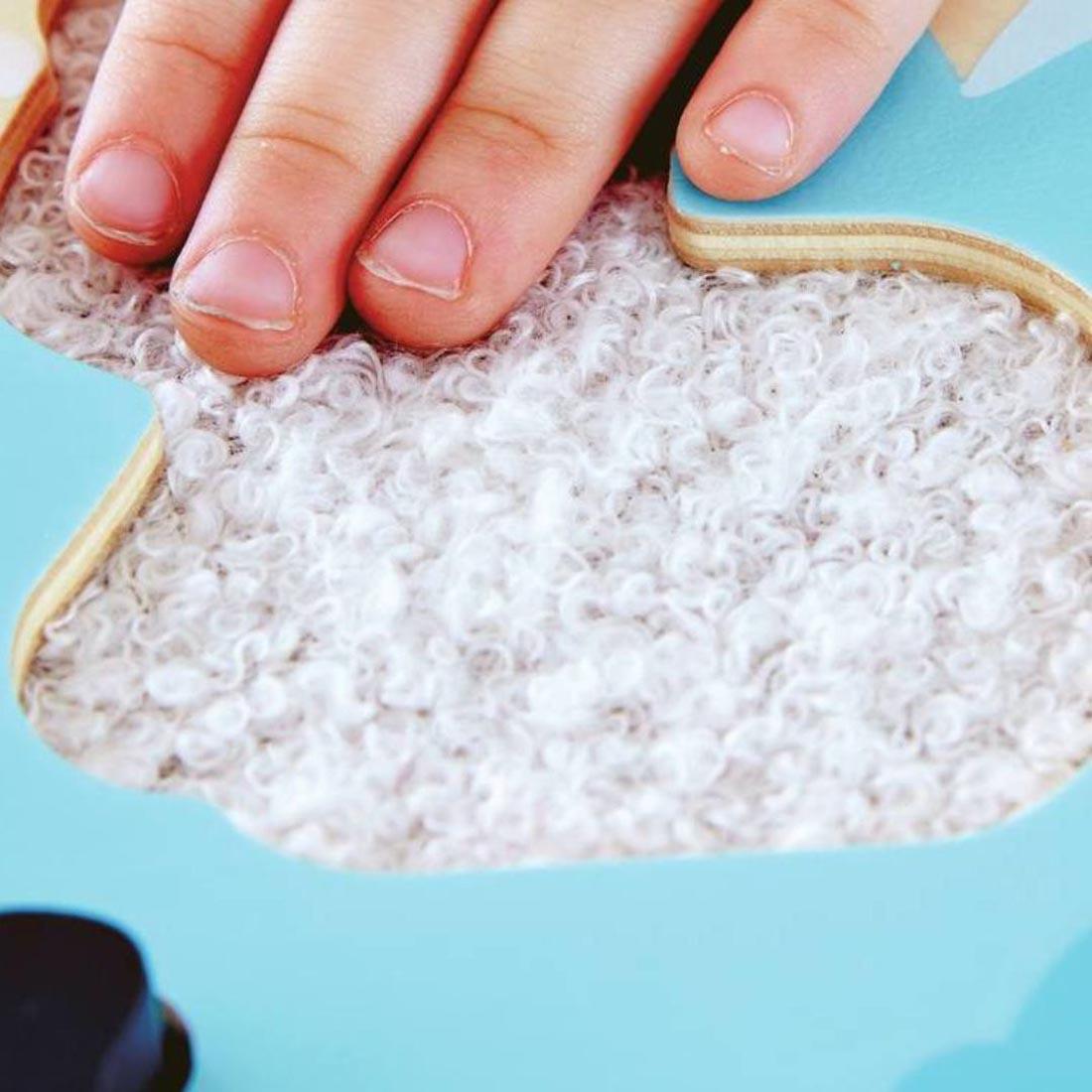 child's hand touching one of the textures on the Hape Polar Animal Tactile Puzzle