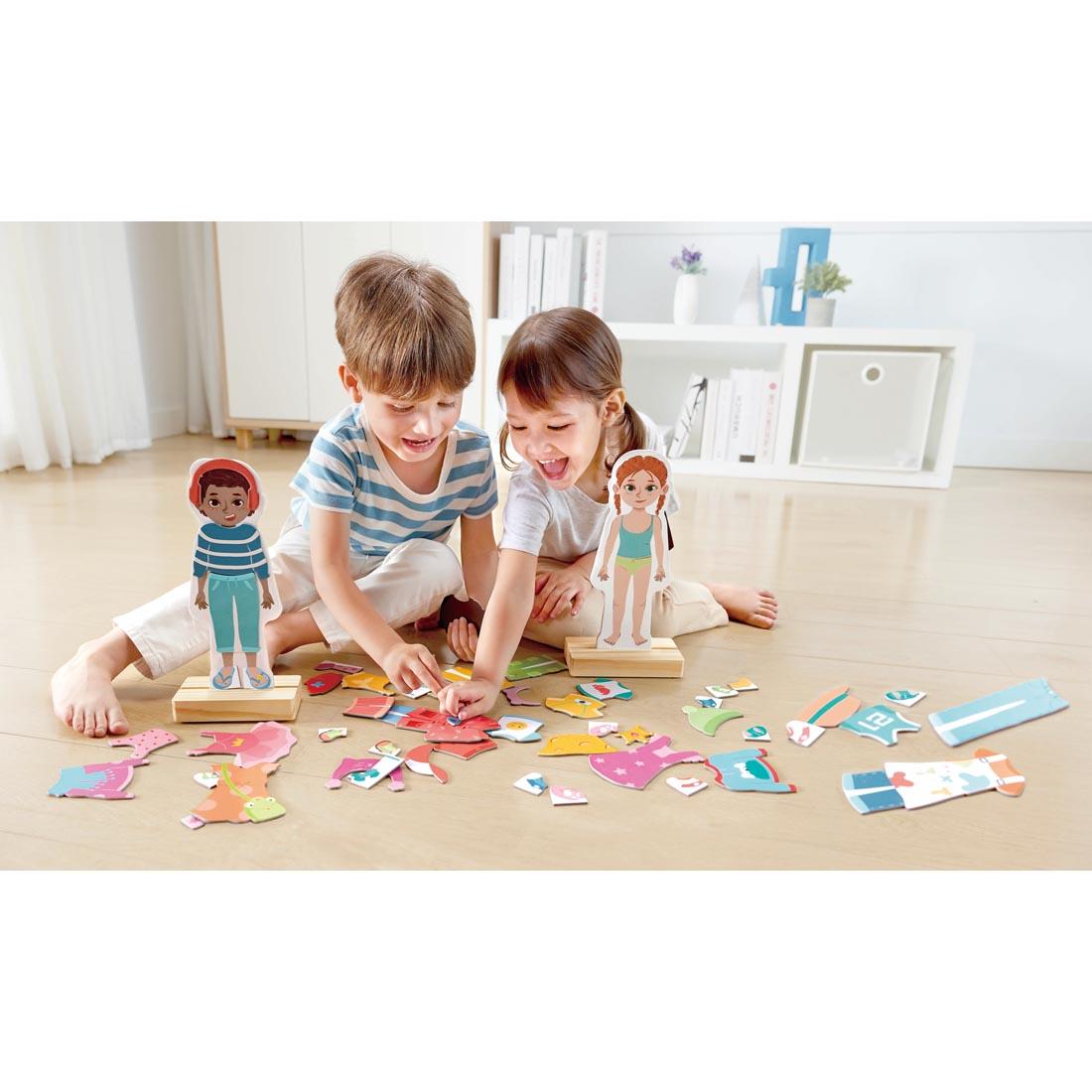 2 children on the floor playing with the Dress-Up Magnetic Puzzle By Hape