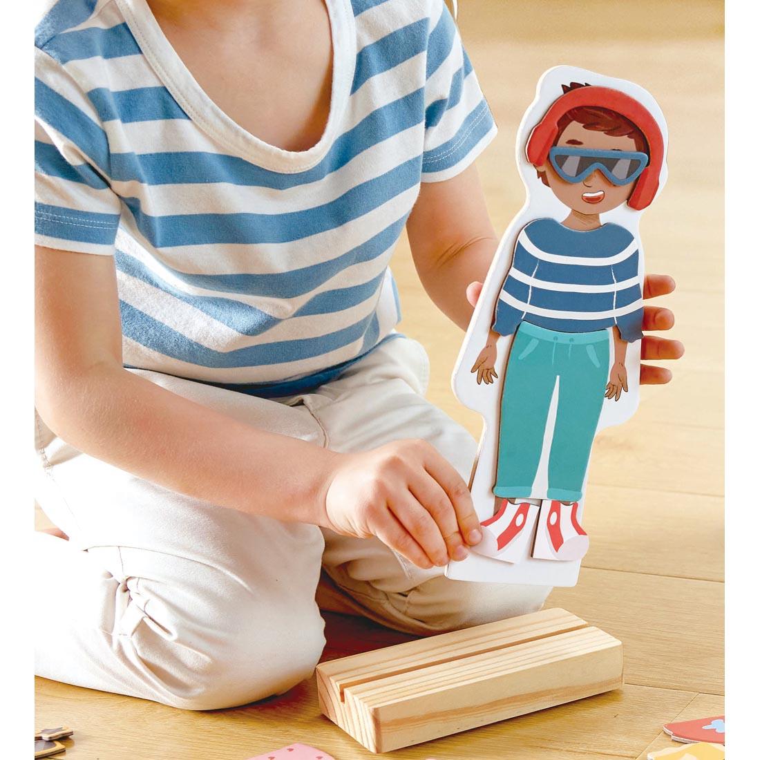 child's hands holding a character from the Dress-Up Magnetic Puzzle By Hape