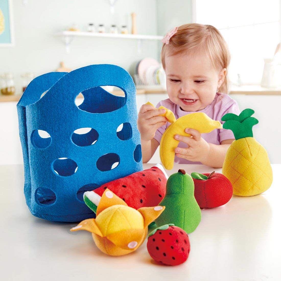 Child playing with the Toddler Fruit Basket By Hape