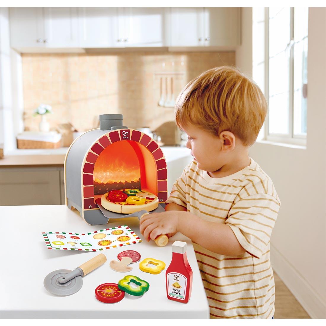 child playing with the Light & Sizzle Pizza Oven Play Set By Hape