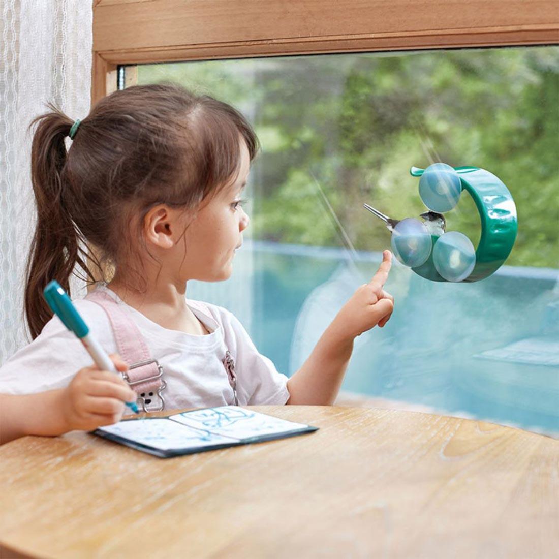 child pointing out the window at a bird on the Hape Window Bird Feeder