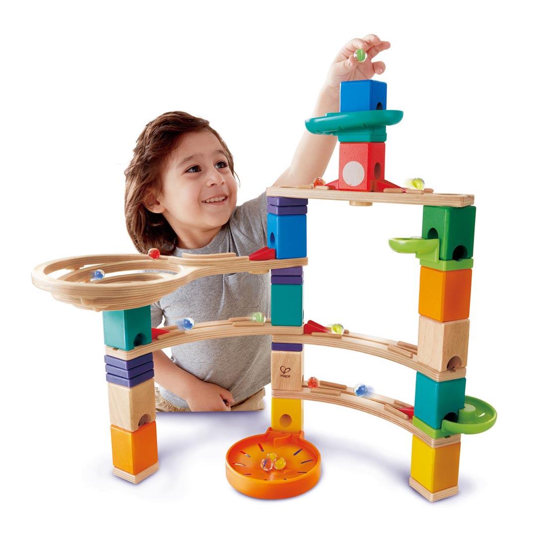 Child playing with an assembled Quadrilla Cliffhanger Wooden Marble Run Set By Hape
