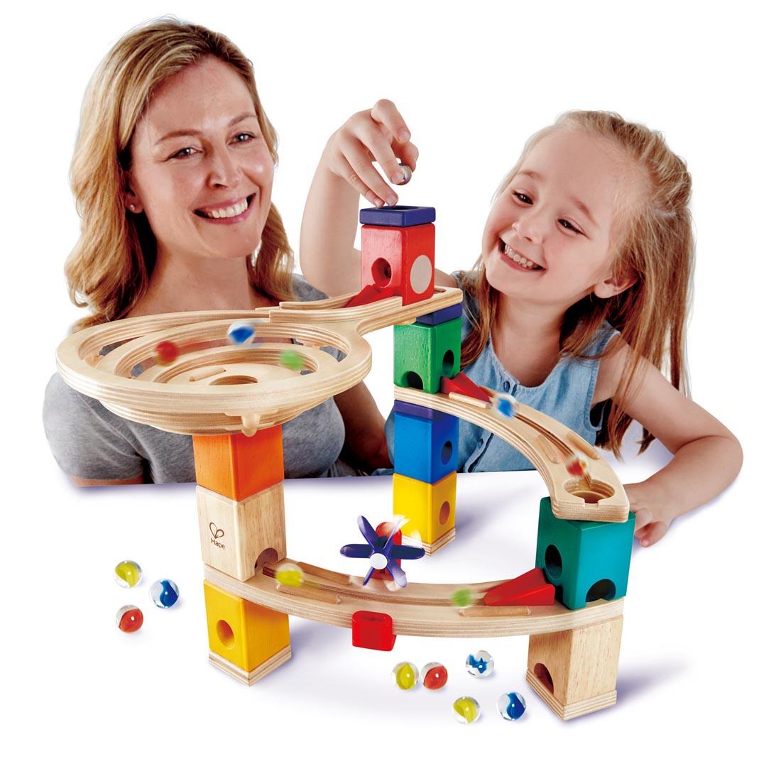 Child and adult playing with an assembled Quadrilla Race To The Finish Wooden Marble Run Set By Hape