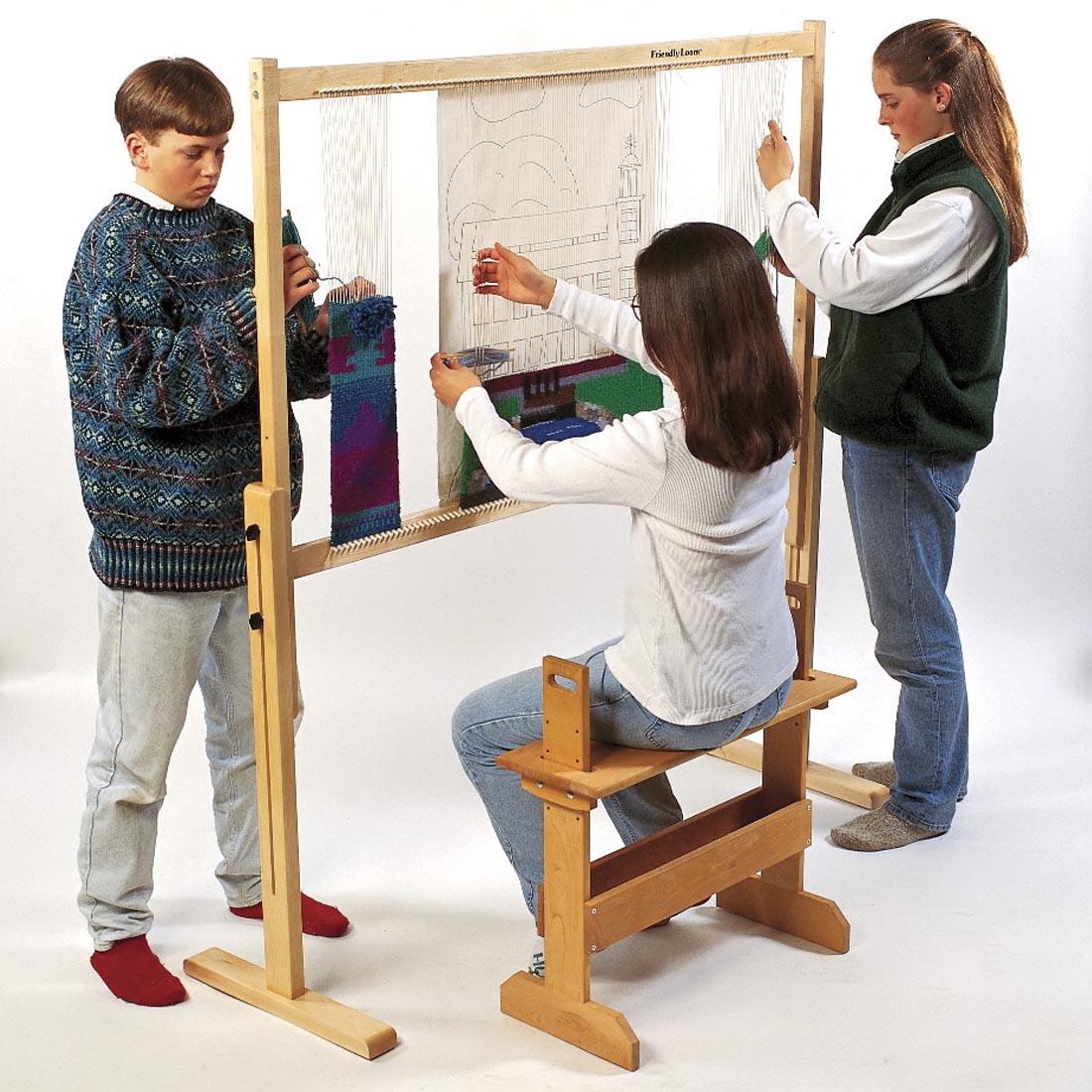 one child sitting and two children standing at the Harrisville Designs Tapestry Loom