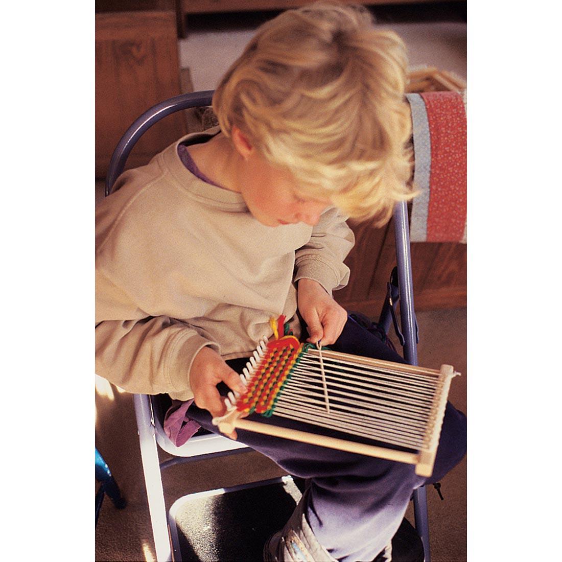 young boy sitting and using the Friendly Loom pegLoom