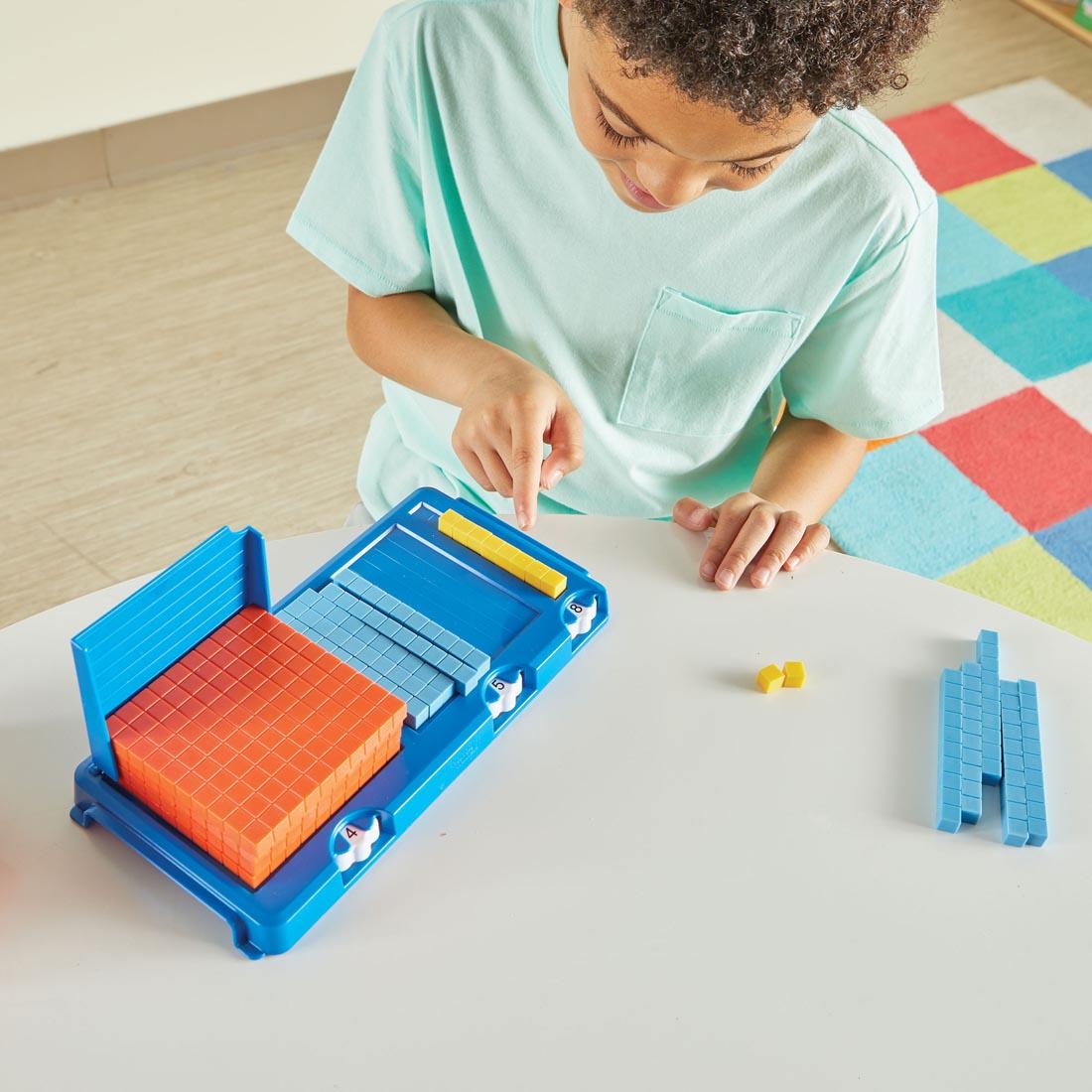 Child using Place Value Frame with various base 10 blocks