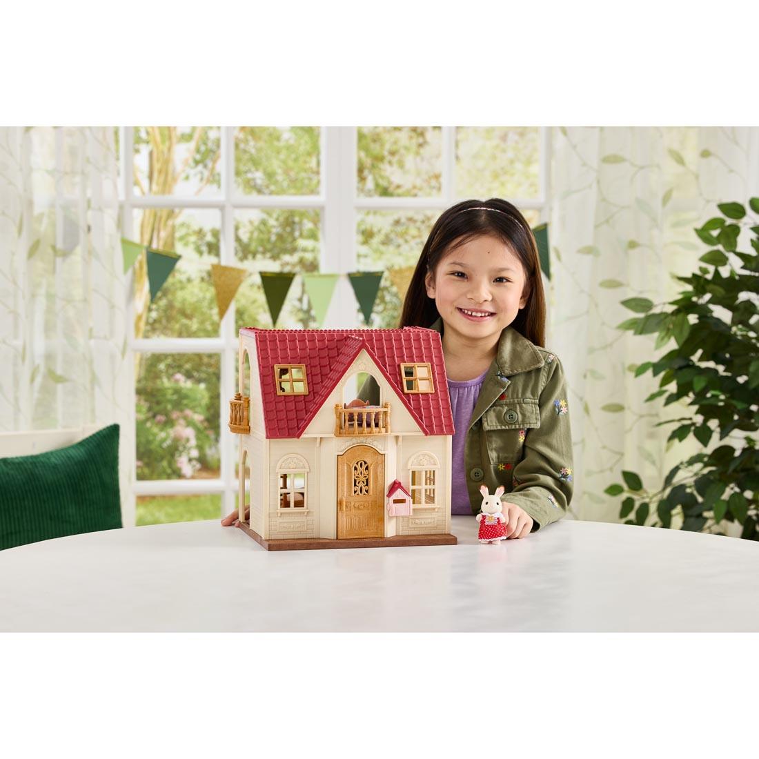 Girl playing with Calico Critters Red Roof Cozy Cottage Starter Home