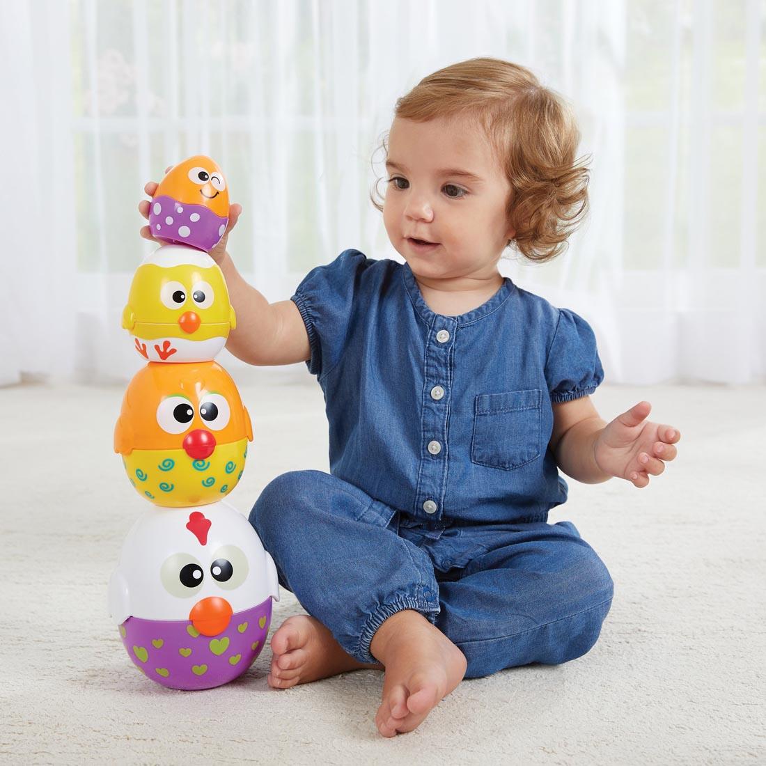 Child sitting and playing with the Chicken 'n Egg Stackers