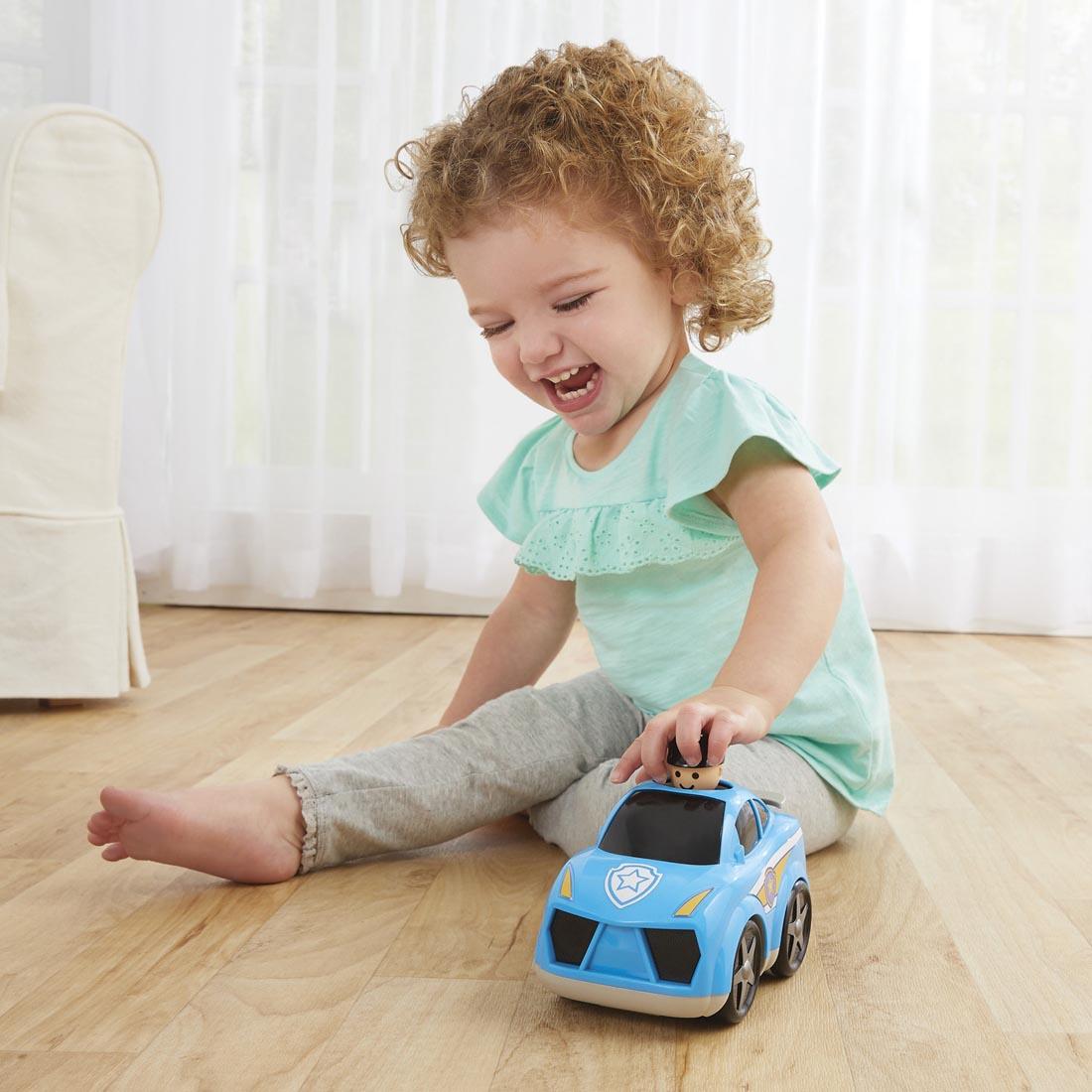 Child on the floor with the Kidoozie Press 'n Zoom Police Car