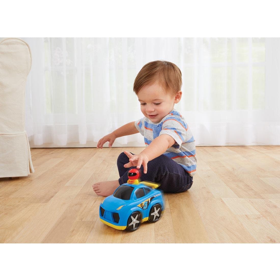 Child on the floor with the Kidoozie Press 'n Zoom Race Car