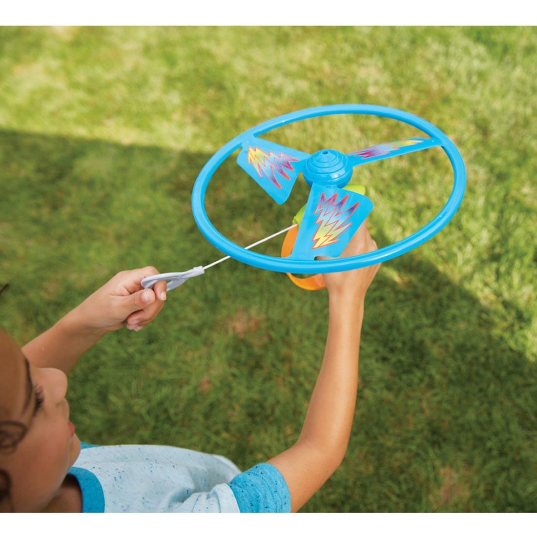 child pulling the cord on the Ripcord Flying Disc By Kidoozie