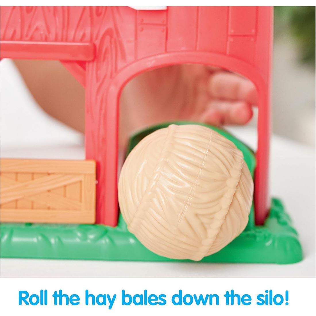 hand playing with the Barnyard Farm Playset By Kidoozie plus text Roll the hay bales down the silo!