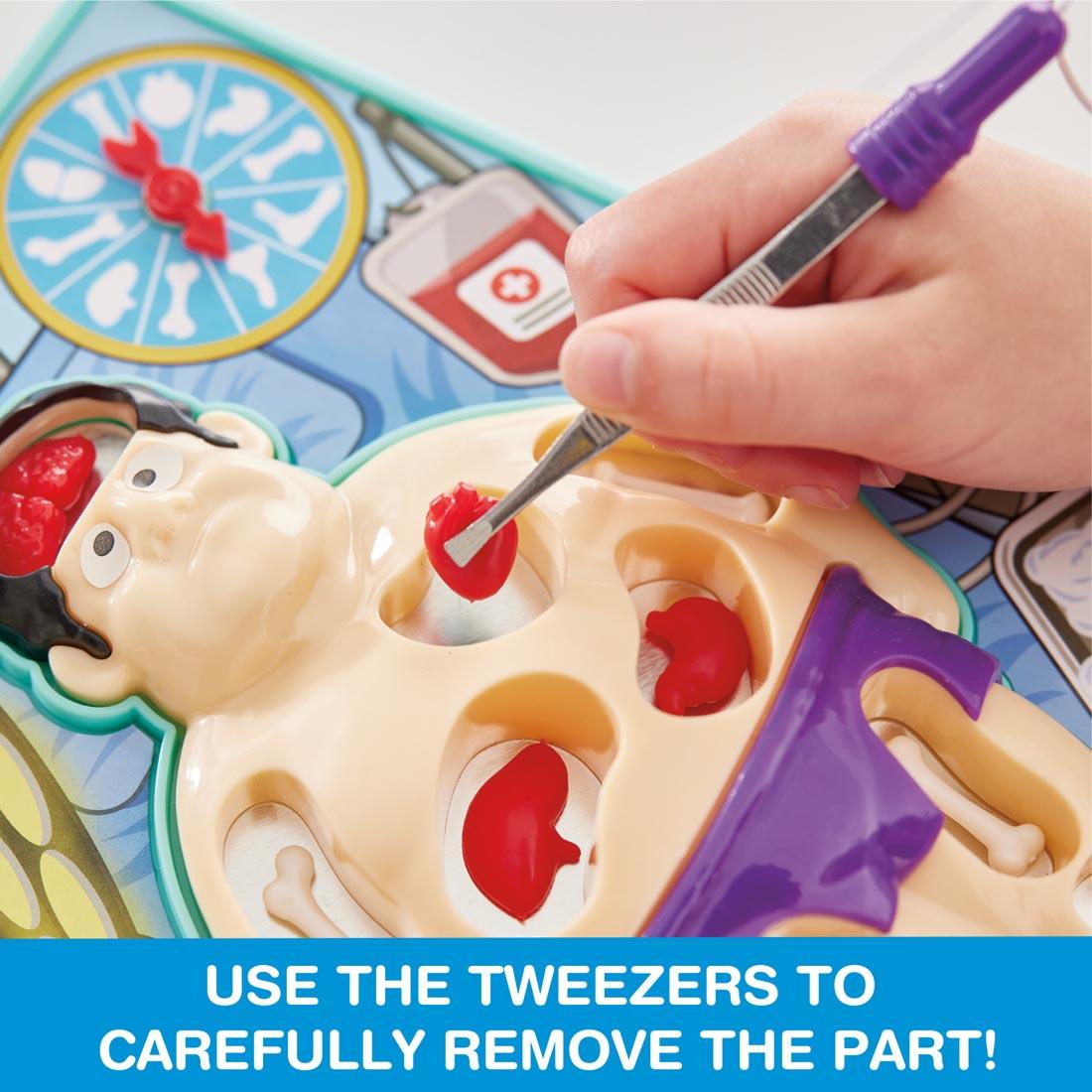 Hand using tweezers to remove the heart from the patient while playing Doctor's Dilemma game, with the words: Use the tweezers to carefully remove the part!