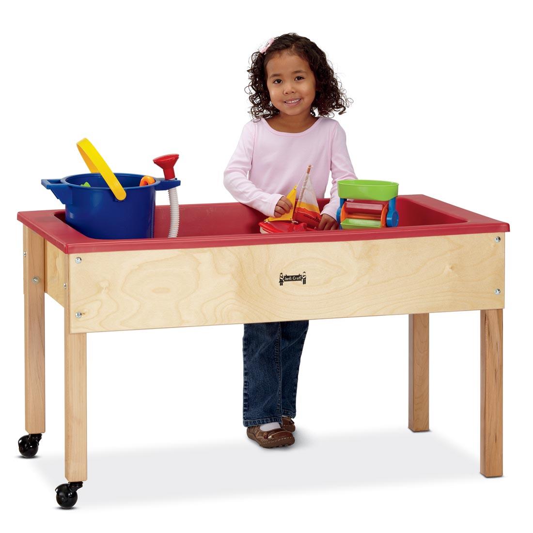 Child standing at a Sensory Table playing with a boat