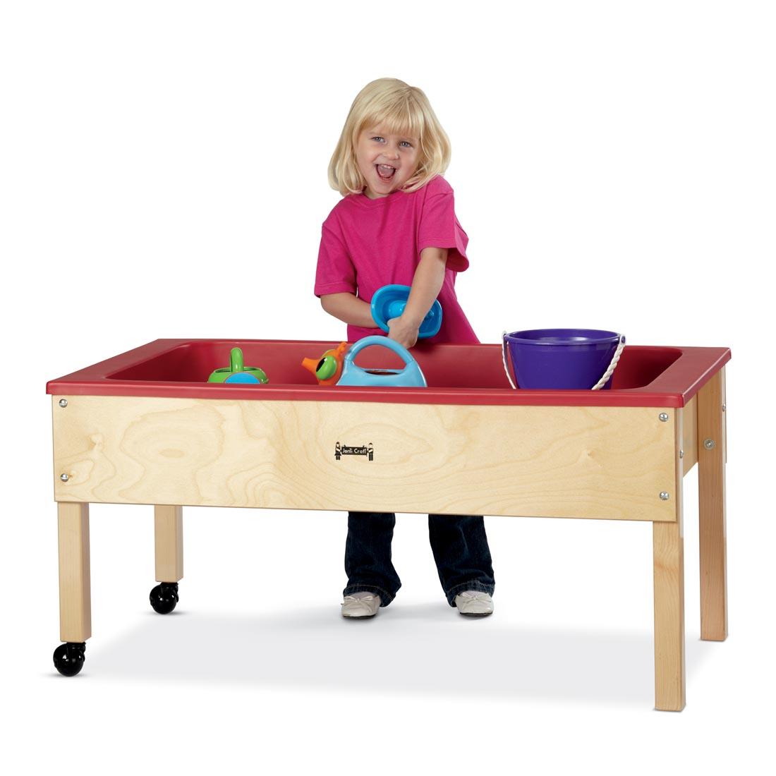 Child standing at a Sensory Table playing with water toys