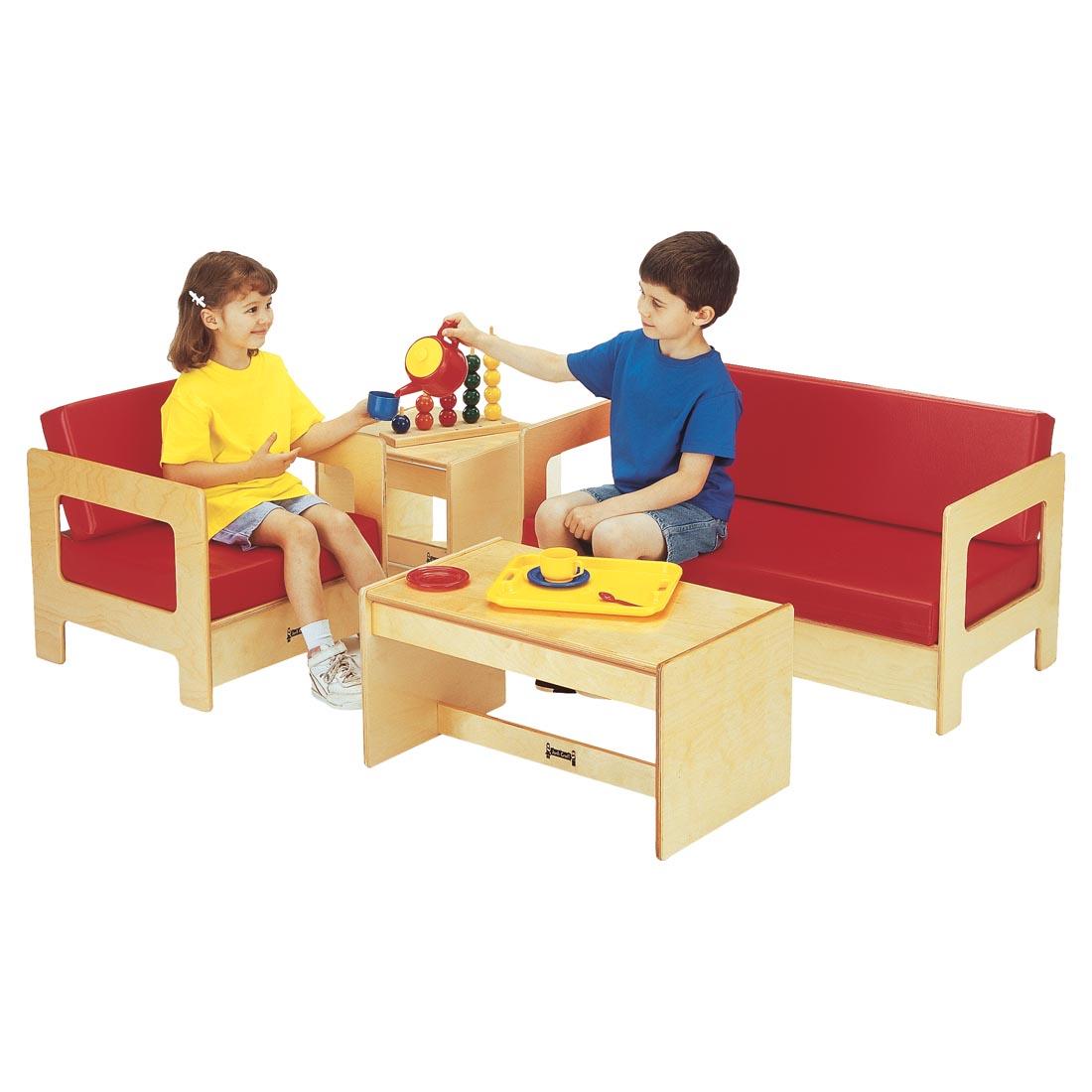 Two children having a tea party in the Living Room Set With Red Cushions