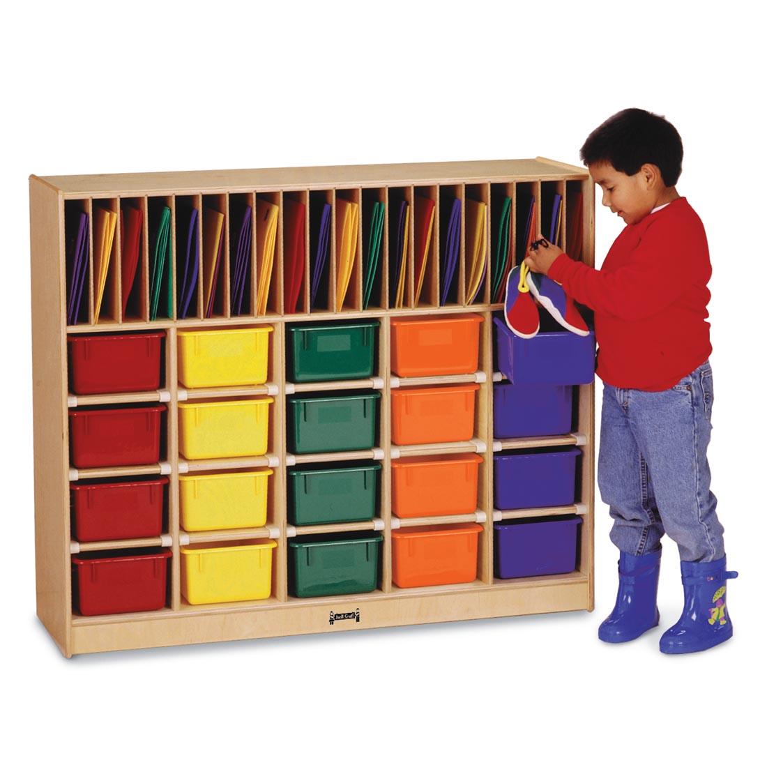 Child standing next to the Classroom Organizer With Colored Trays shown with suggested storage contents