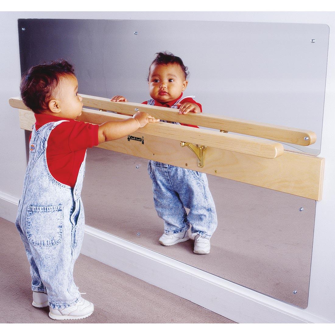 Baby standing in front of the Infant Coordination Mirror