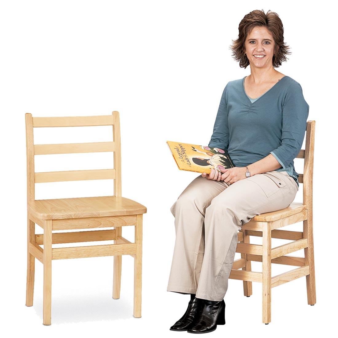 An adult sitting in a Ladderback Chair with an empty one beside