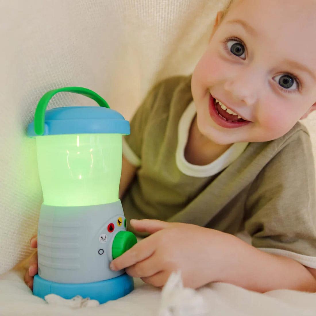 child under a blanket playing with the Let's Explore Light & Sound Lantern Play Set By Melissa & Doug