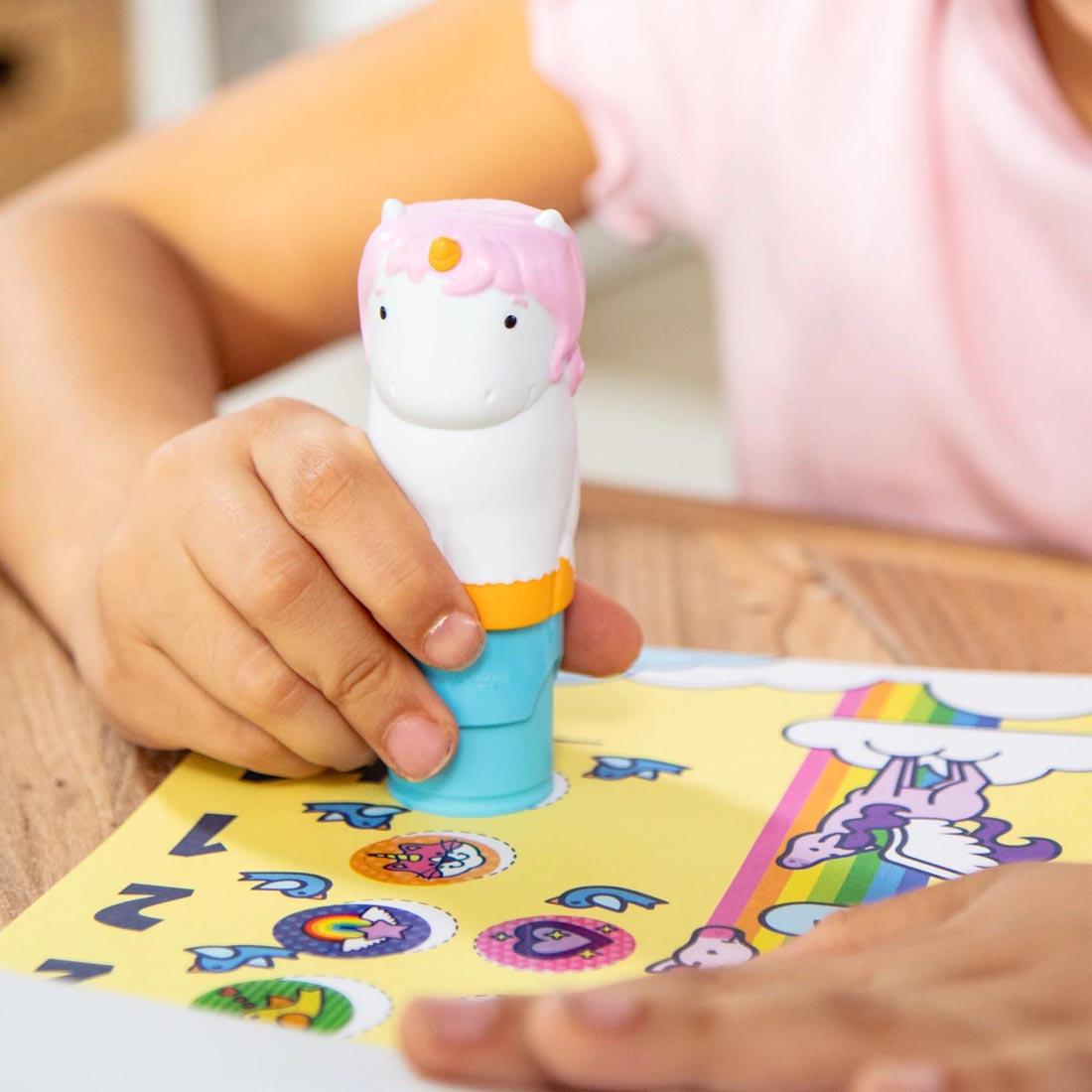 child's hands using the stamper from Unicorn Sticker Wow! Set By Melissa & Doug