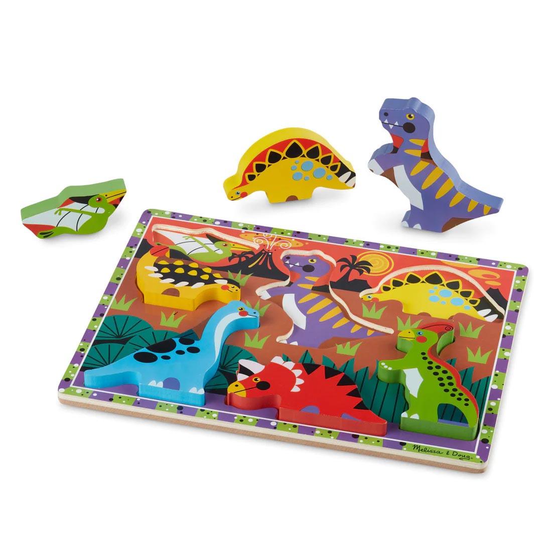 Dinosaurs 7-Piece Chunky Puzzle By Melissa & Doug with three of the pieces beside the board