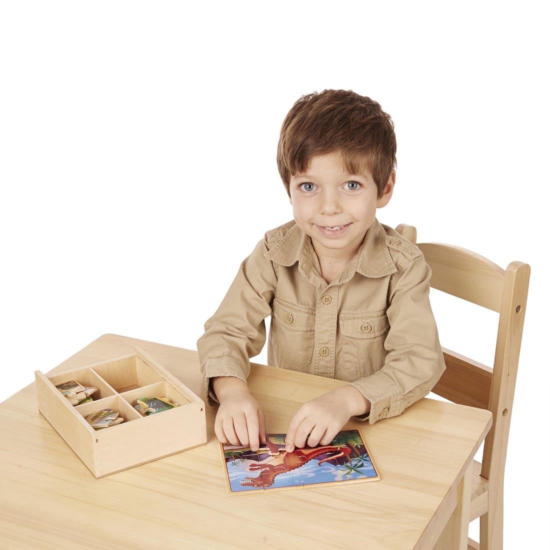 Child at a table with one of the Dinosaurs Wooden Jigsaw Puzzles in a Box By Melissa & Doug