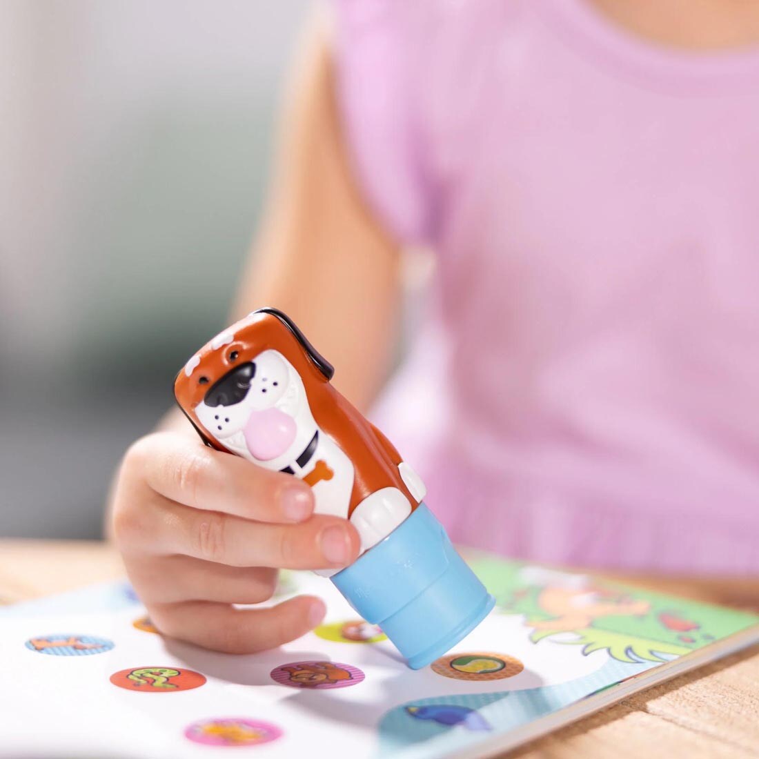 child's hand holding the stamper from the Dog Sticker Wow! Set By Melissa & Doug