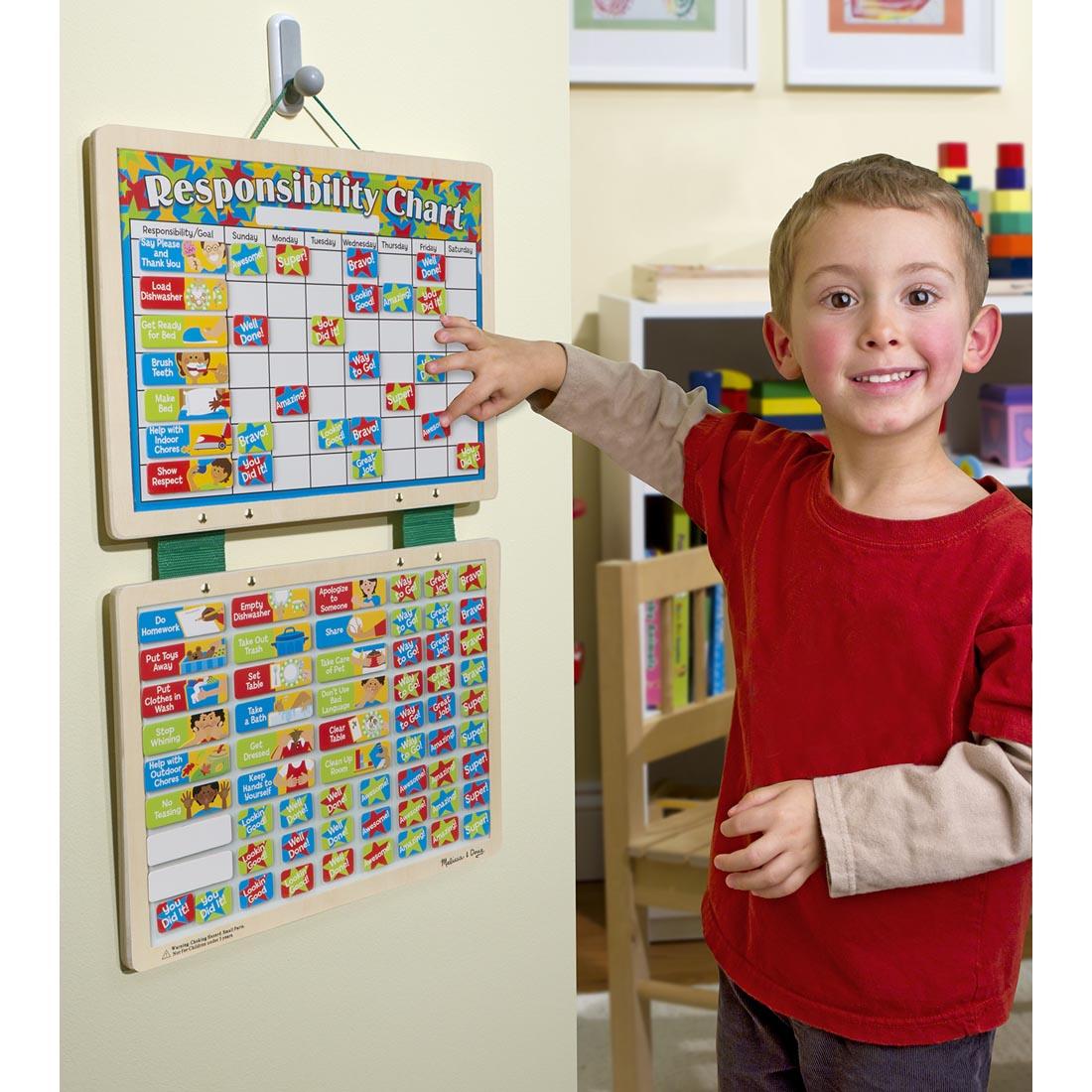 child standing next to the hanging Magnetic Responsibility Chart