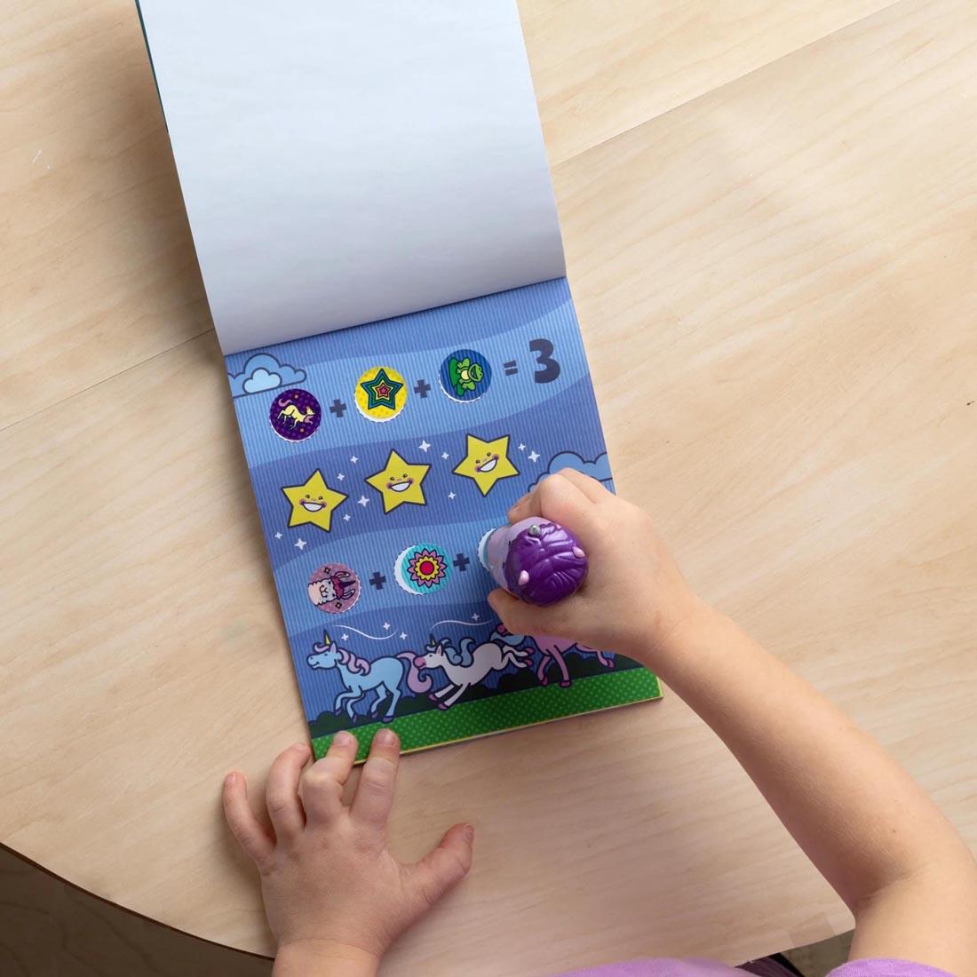 child's hands using the Purple Unicorn Sticker Wow! Set By Melissa & Doug