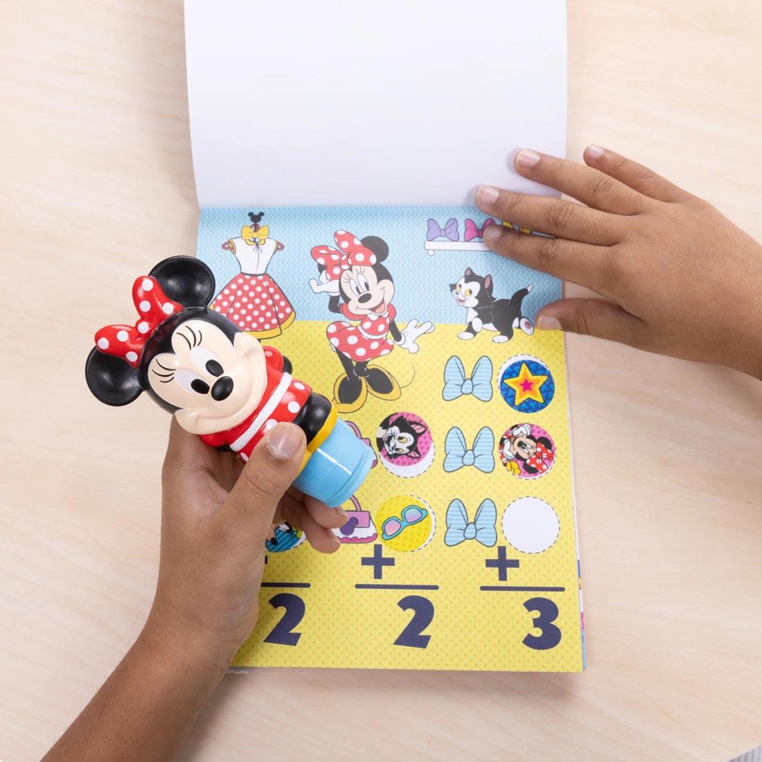 child's hands using the Minnie Mouse Sticker Wow! Set By Melissa & Doug
