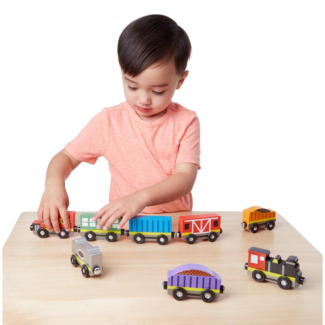 child playing with Melissa & Doug Wooden Train Cars