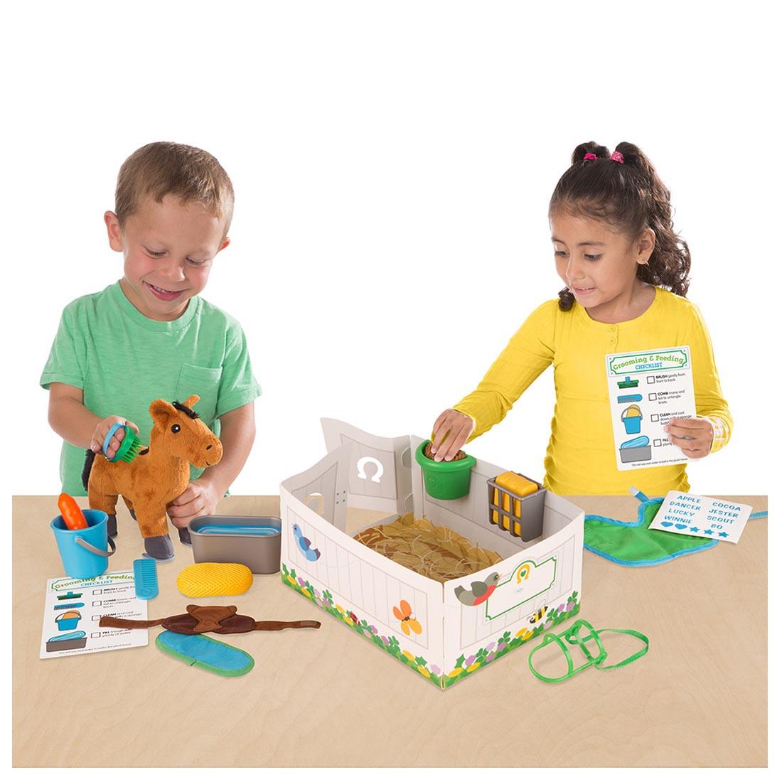Two children playing with the Feed & Groom Horse Care Play Set by Melissa & Doug