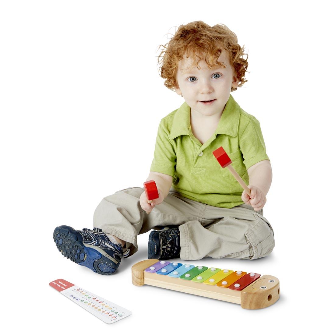 child holding the mallets of the Wooden Caterpillar Xylophone