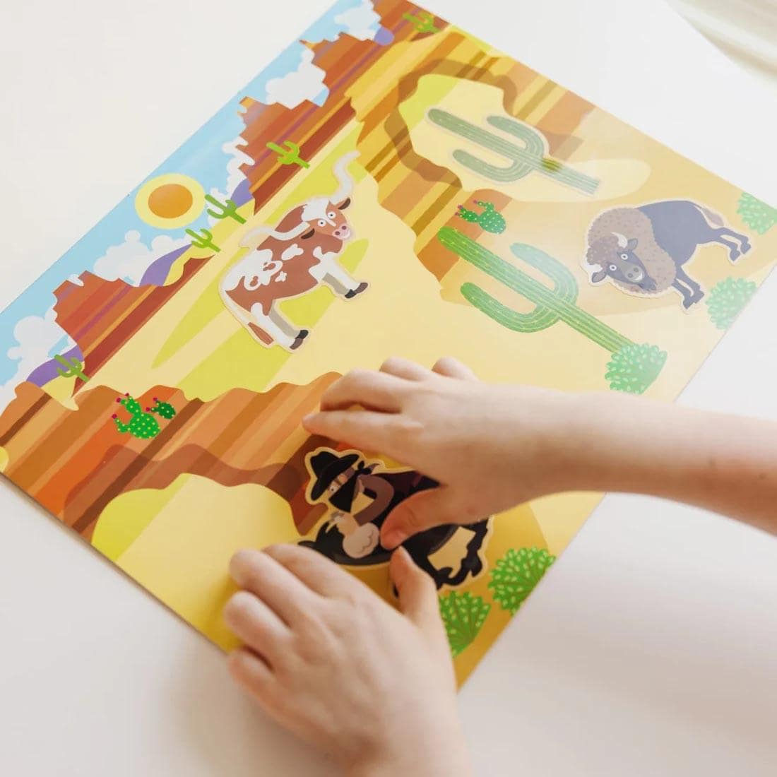 child's hands using the Adventure Reusable Sticker Pad By Melissa & Doug