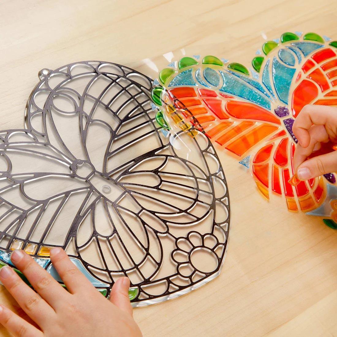 child's hands completing a Melissa & Doug Stained Glass Made Easy Butterfly