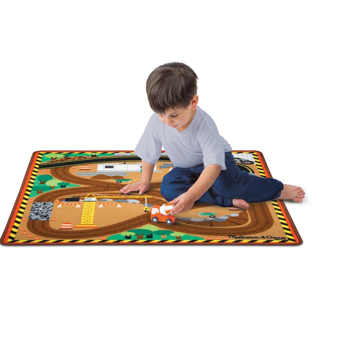 child playing with the Melissa & Doug Round The Construction Zone Work Site Rug and Vehicle Set