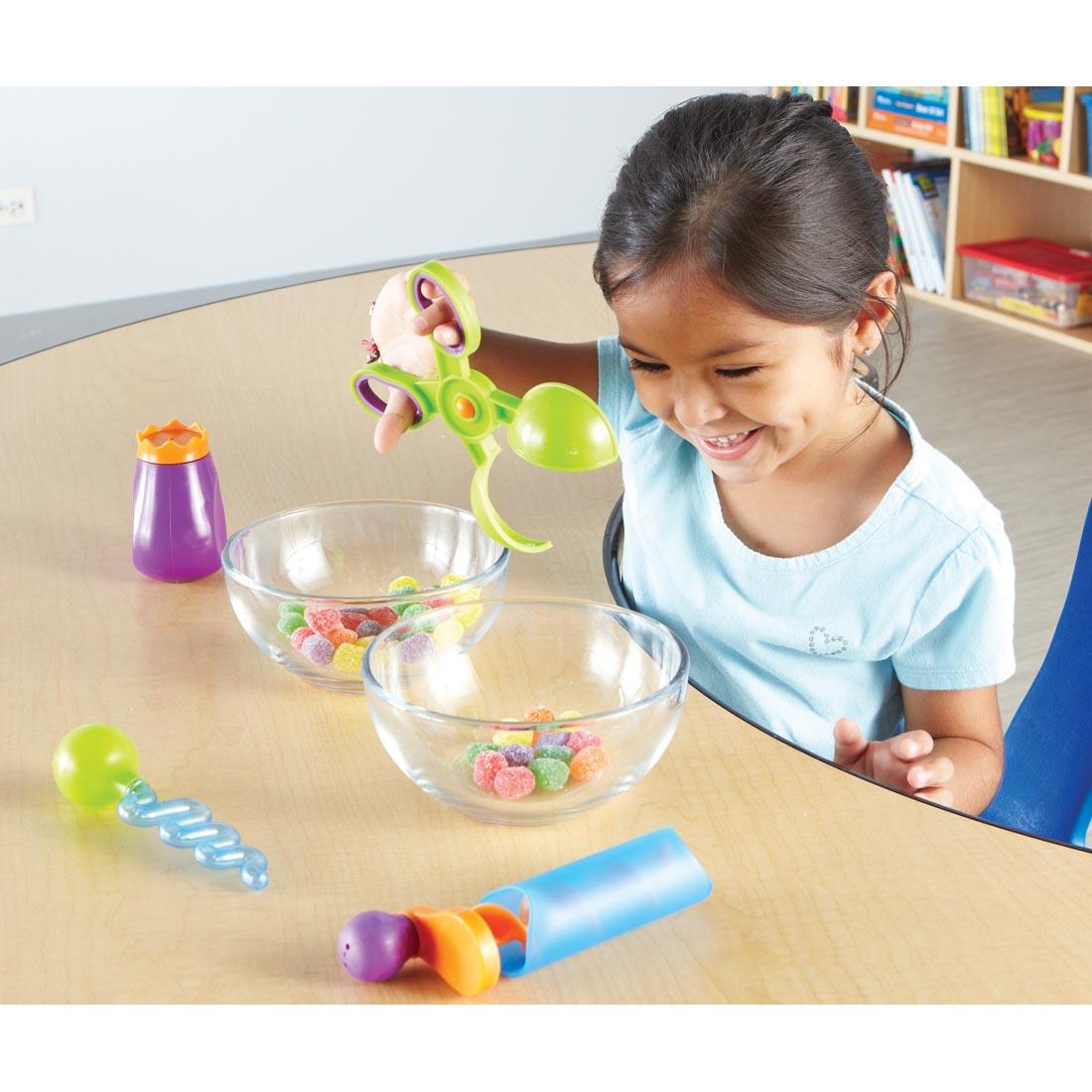 child using one of the squeeze tools from the Sand & Water Fine Motor Tool Set