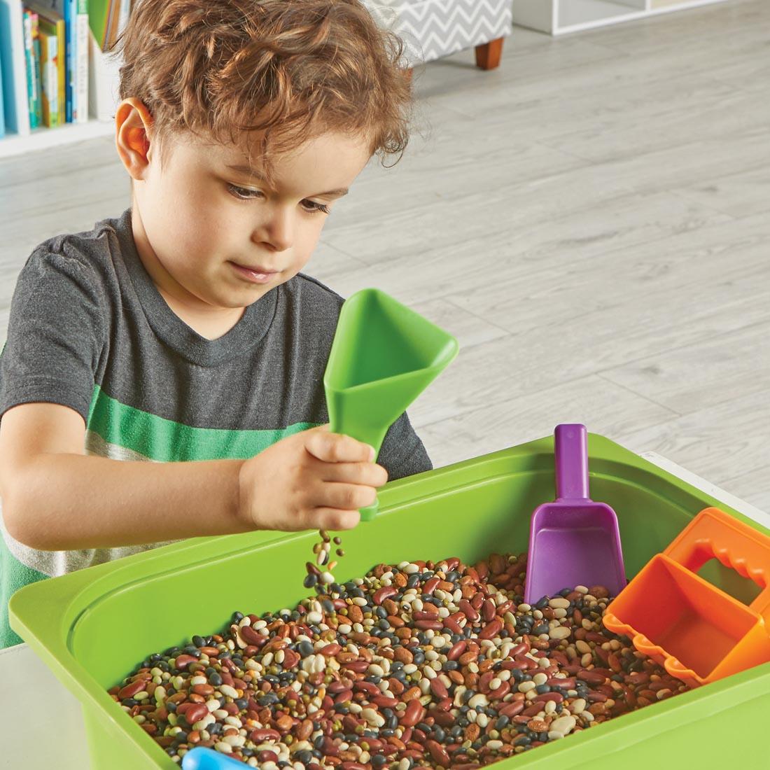 child using the Helping Hands Sensory Scoops with a bin of beans